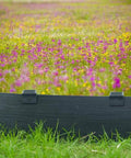 Black bender board installed in garden with colorful wildflowers, secured by 24 Pack 10 Inch Heavy Duty Metal Landscape Edging Stakes Galvanized Spikes