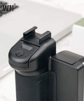 Close-up of compact phone camera grip handle with tripod mount remote shutter and cold shoe adapter for iPhone and Samsung smartphones.