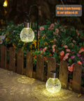 4 Pack Solar Lanterns With Shepherd Hooks No Wiring Easy Setup Outdoor Color Changing Crackle Glass 3 Lumens Waterproof Garden Lights For Pathway Backyard Decor illuminating a flower bed at night.