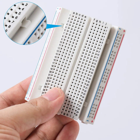 Hand holding a Six-Piece 400-Pin Solderless Breadboard Set for DIY Prototyping with close-up of solid hole alignment detail.