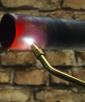Oxypropane Welding Gas Cutting Torch Kit with brass fittings in use, heating metal pipe against brick wall backdrop.