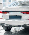 Rear view of a white car with a mounted black license plate, featuring Black License Plate Screw Cap Kit With Eight Caps For Frame Bolts.