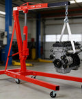 Hella Sturdy Heavy Duty Hydraulic Engine Hoist Crane Two Ton Four Thousand Pounds Capacity Folding Cherry Picker With Six Swivel Casters For Garage Work Red lifting an engine in a workshop.