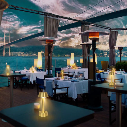 Outdoor restaurant with Cordless Gold Battery Operated Table Lamp For Dining Ambience on tables overlooking waterfront.