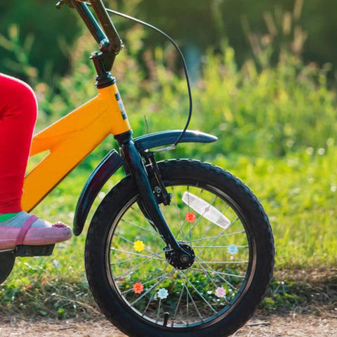 Child's bike with 30 Pcs Flower Shaped Bicycle Spoke Beads Set For Wheel Spokes Plastic Clip Beads Decorations visible on wheel.