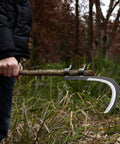 Person holding All-Purpose Garden Sickle With Replaceable Wooden Handle And Heavy-Duty Manganese Steel Blade for yard cleanup