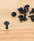 Close-up of 120 Piece Size Eight Phillips Truss Head Black Wood Screw Kit for Wall Plates and Woodworking Self Tapping Fasteners on wood surface.