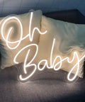 Dimmable LED Neon Sign With Transparent Acrylic Backplate, Indoor Wall Decor In Warm White, Oh Baby design on couch