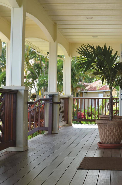 Covered porch with wooden decking, potted plant, and railing, showcasing a cozy outdoor living space.