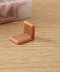 Universal L Shape Drawer Glides Kit 50 pieces tack in drawer sliders for furniture showing one brown plastic glide on a wooden surface