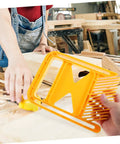 Badass Grip Featherboard Safety Clamp For Circular And Band Saws held in hand above workbench for secure cutting setup.