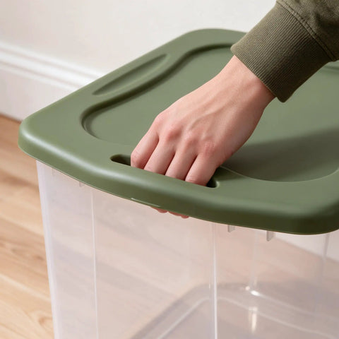 Hand gripping the lid of the Rock Solid 95 Quart Clear Plastic Storage Bin With Easy Grip Handles for organization.