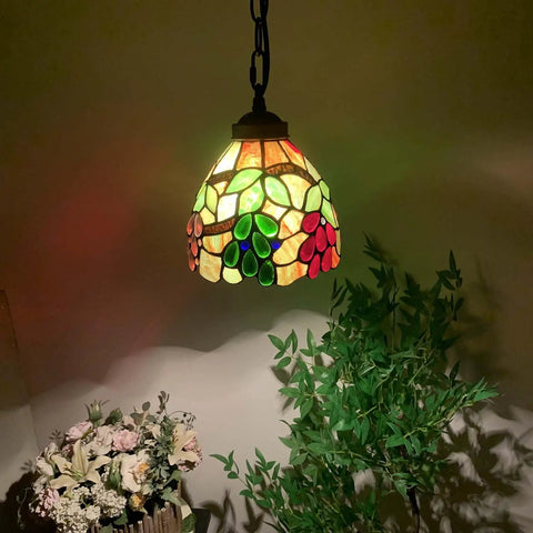 Grape Tiffany Style Stained Glass Ceiling Pendant Light with 7-inch lampshade, handcrafted glass panels and bronze chain in dark room.