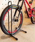 Portable Single Bike Stand For 20 To 28 Inch Wheels And Up To 2.5 Inch Wide Tires, holding a bike in a garage setting.