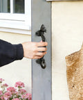 Person opening a door with a Two Pack Seahorse Cast Iron Door Handles Set, Heavy Duty Rustic Barn Cabinet Pulls For Farmhouse Drawers, Garage, Gate, Shed And Sliding Doors, Vintage Decorative Hardware attached.