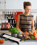 Gramercy adjustable mandoline slicer in black on a kitchen counter beside fresh vegetables