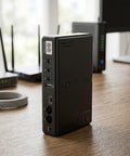 Premium Adjustable DC Ups Battery Backup For Home Routers Modems And Security Cameras With Smart Chip Management and Plug And Play Convenience For Zero Headache Setup side view showcasing connectors on a wooden desk.