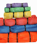 Stack of multicolored nylon round slings in various sizes for industrial lifting and crane applications.