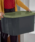 Roomy 17.5 Gallon Plastic Storage Bin With Secure Stackable Lid And Opaque Base held by a person, showcasing full grip handles.