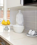 Round Pop Up Floor Outlet Box With 20 Amp USB Tamper Resistant Receptacle ETL Listed on kitchen countertop next to decor
