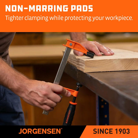 Two Jorgensen steel bar clamps (orange/black) securing wood on a workbench.