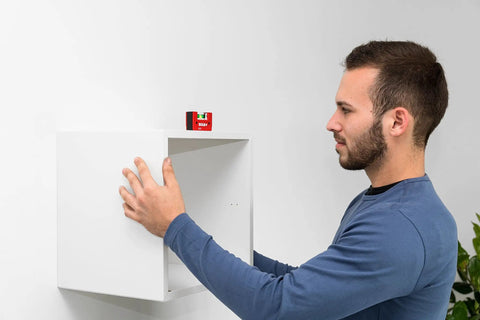 Man using Sola Spirit Level Compact Go! Clip, 0 to align a white shelf, demonstrating its compact and handy features.