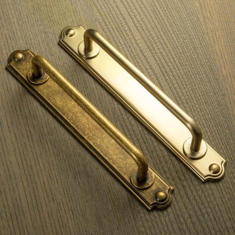 Antique Brass Drawer Pulls With Backplates Five Point Zero Four Inch Center To Center Zinc Alloy Cabinet Handles on wood surface