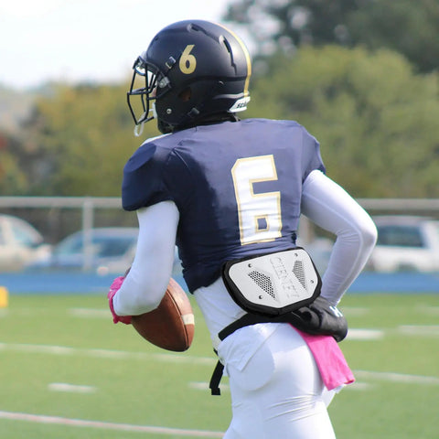 Football player wearing high impact football back plate for shoulder pads universal youth and adult protection on the field.