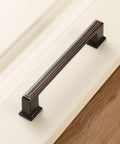Stepped Bar Cabinet Pull in Oil Rubbed Bronze, 5 Inch Screw Spacing on white cabinet surface