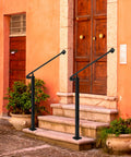 Heavy Duty Adjustable Stair Handrail Rock Solid Wall And Floor Mounted Wrought Iron Safety Rail Built Tough For One To Three Steps No Sweat Installation In Matte Black Steel near a door with stone steps.