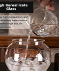 Pouring water from a glass vessel into a large glass bowl with ice, showcasing the Large Capacity Cold Brew Coffee Maker Tower.