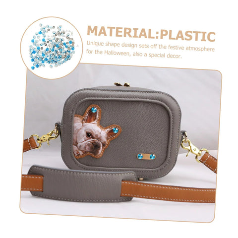 Front view of gray faux-leather mini crossbody bag with blue studs, dog-face patch, gold hardware, brown strap.