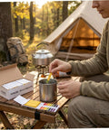 Person using All Purpose Litmus Paper 1-14 Acid Test Strips Kit, Ten Pack For Wet Soap, Lemon Juice, Milk, Detergent, Wet Soil, Saliva, Sweat, And Aquarium Water Testing, Great For At Home Lab Use on a camping table.