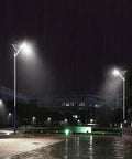 JUDYSSY Outdoor Solar Powered Street Flood Lights-400W Dusk to N illuminated at night in rain, showcasing bright LED illumination.