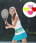 Woman playing tennis with heart shaped tennis dampeners set of 4 silicone vibration absorbers for rackets in red pink yellow purple
