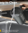 Cleaning the 4 In 1 Milk Frother And Warmer With Stainless Steel Build And Touch Screen under running water in a kitchen sink.