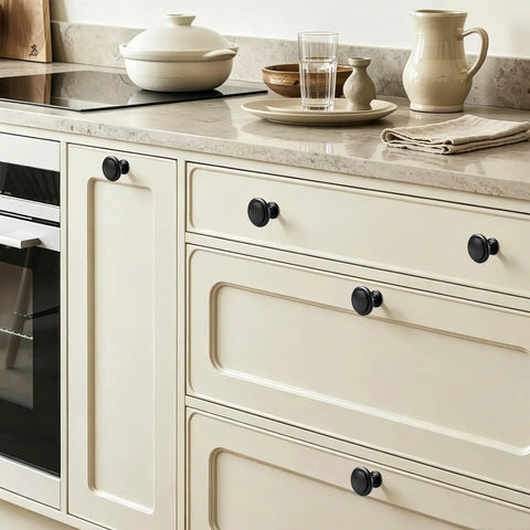 Slick Matte Black Cabinet Knobs Heavy Duty Zinc Alloy on cream kitchen drawers, smooth grip, easy install, solid wide base.