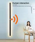 JGSYD Smart Sensor Control Wall Light with Motion Sensor Led Wall Lamp Acrylic Wall Mounted Long Strip Wall Sconce Minimalist Soft Light for Courtyard Hallway,White Light-100Cm next to a person sitting in a chair.