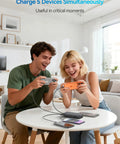 Two people using devices while charging with Ride Or Die Portable Charger With 32000Mah Capacity And Built In Cables Featuring Usb C Fast Charging For Phones Tablets All Day Juice Hardcore Build Quality.