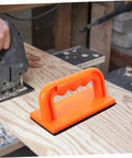Orange Safety Push Block for Table Saws and Router Tables on a woodworking bench, guiding wood safely with precise control.