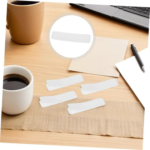 100 Pack Double Sided Hook And Loop Strips With White Pet Film Backing 2.5x10cm on a wooden desk beside a coffee cup.