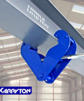 Karryton blue I-beam lifting clamp attached to a gray steel beam in a warehouse (side view).