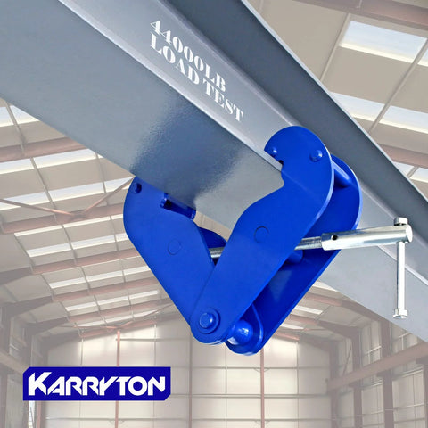 Karryton blue I-beam lifting clamp attached to a gray steel beam in a warehouse (side view).