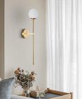 Mid Century Modern Long Wall Sconce In Brushed Brass For Bathroom Vanity Lighting Gold Globe Wall Light With White Glass Sphere Shade Antique Brass Finish Copper And Glass Sleek Dope Wall Lamp mounted on light-colored wall