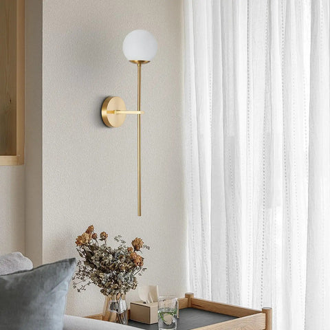 Mid Century Modern Long Wall Sconce In Brushed Brass For Bathroom Vanity Lighting Gold Globe Wall Light With White Glass Sphere Shade Antique Brass Finish Copper And Glass Sleek Dope Wall Lamp mounted on light-colored wall