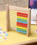 The Real Deal Wooden Abacus For Kids Featuring 100 Brightly Colored Beads Perfect For Kickstarting Math Foundations And Montessori Counting Drills Preschool Classrooms on a yellow table with number cards.
