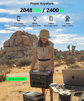 Woman using Infinity 2000 Pro Portable Power Station 2048Wh LiFePO4 Battery in desert setting with laptop and charging devices
