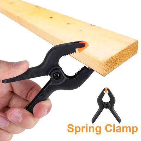3 Inch Plastic Spring Clamps With Killer Anti Slip Grip Heavy Duty Woodworking And Backdrop Clips Hella Handy For Crafts Home Diy Total Flexible Tool Built Tough For Quick Projects holding on to a wooden plank.