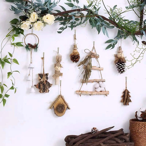 Nature-inspired wall decor with hanging ornaments on a branch, featuring flowers, pine cones, and rustic wooden trinkets.