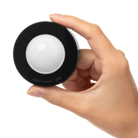 Hand holding black puck light from Under Cabinet Lighting Kit With 6 Wireless Remote Dimmable LED Puck Lights In Black Easy Install Auto Off Timer